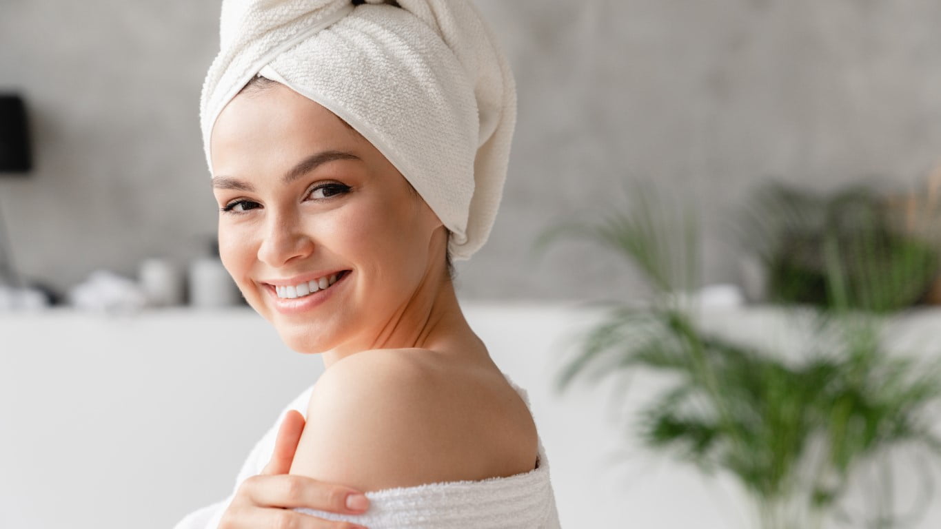 Smiling relaxing young serene woman in bathrobe and towel relaxing after hard day in shower bath.